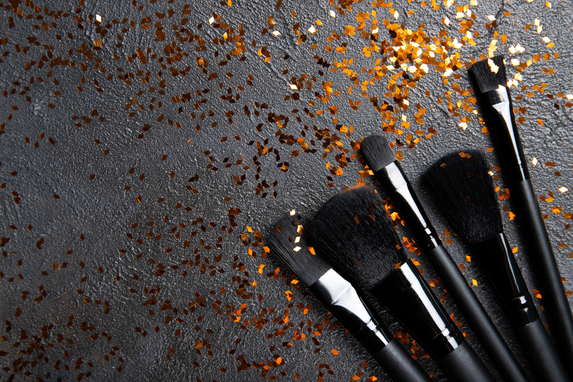 Black makeup brushes and gold sparkles